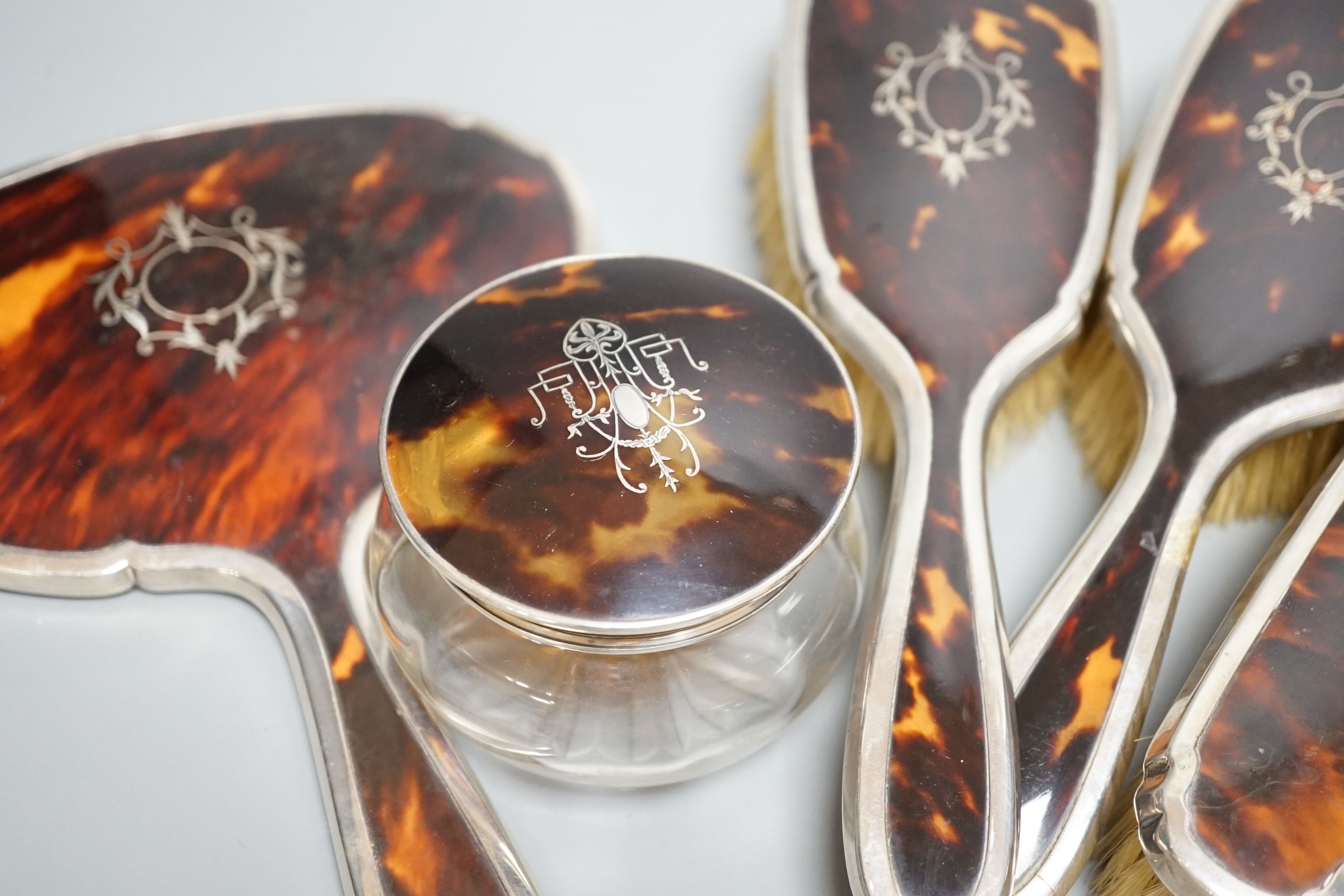 A George V silver and tortoiseshell mounted mirror and brush set, Birmingham, 1928 and a similar powder jar.